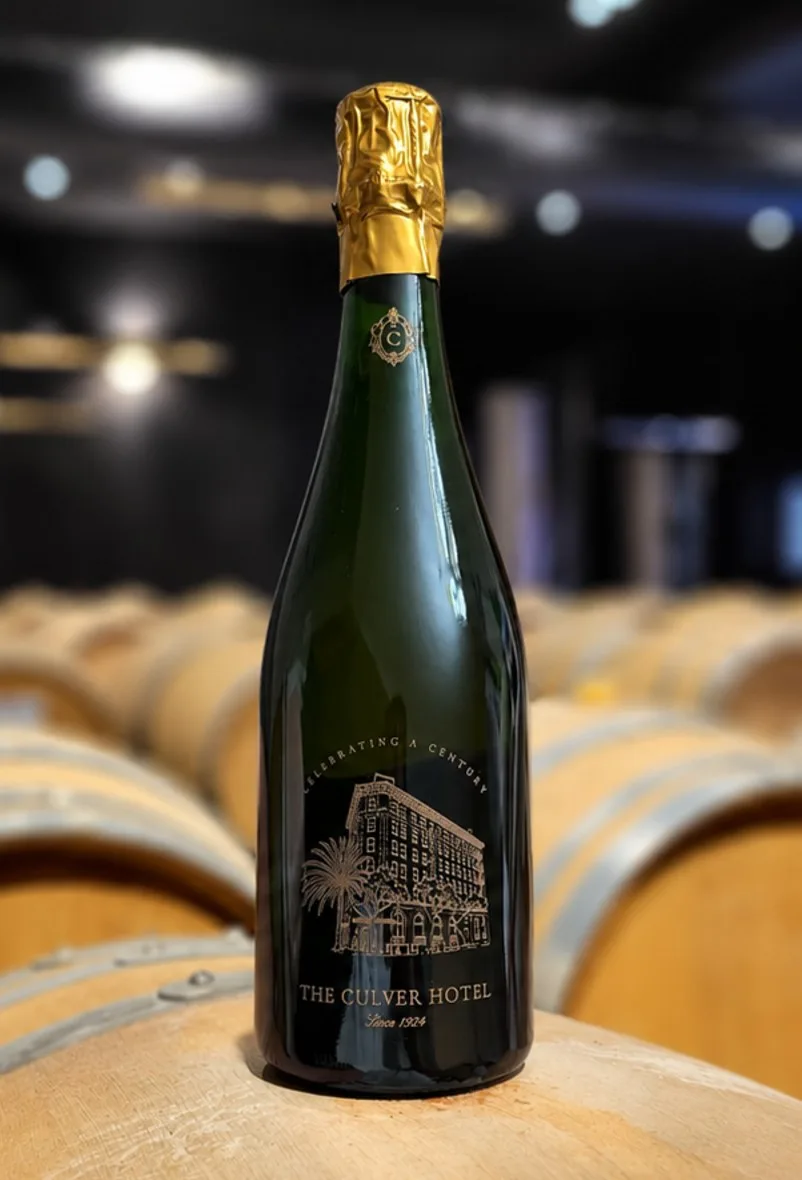 An engraved Brut Assemblage for The Culver Hotel, standing on a barrel in the Tribaut cellar